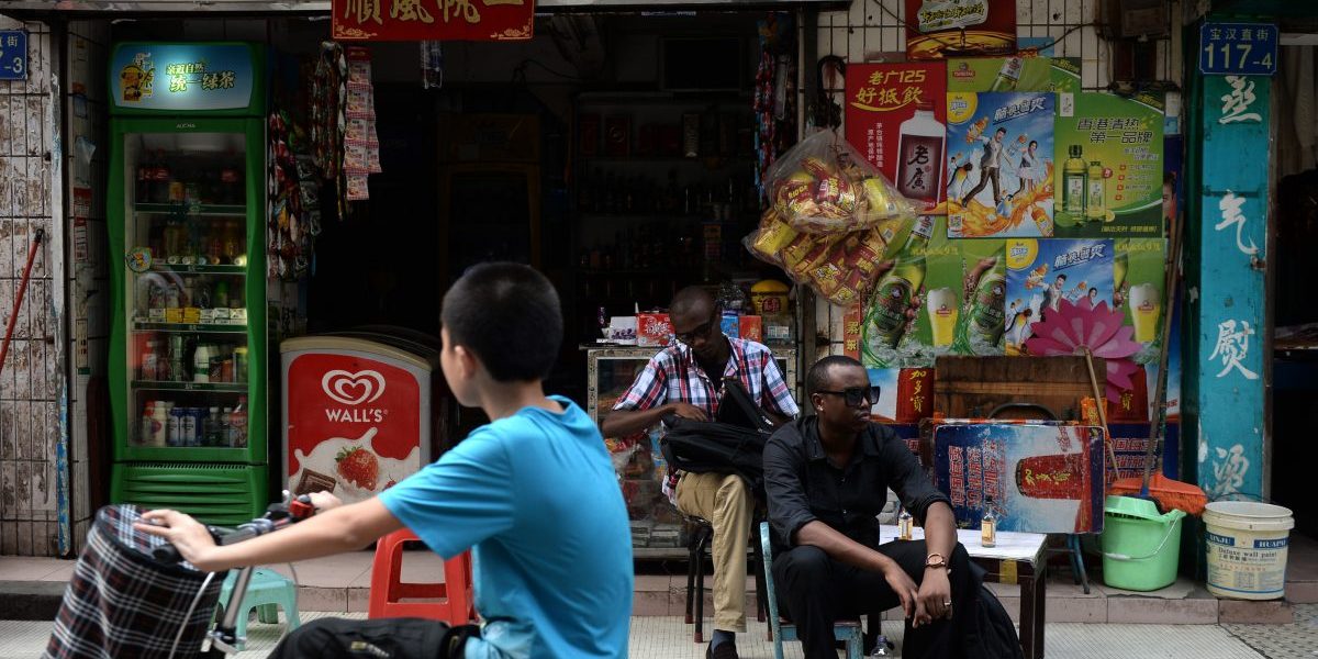 Traders from Africa rest outside a convenience store in Guangzhou. Image: Getty, STR/AFP