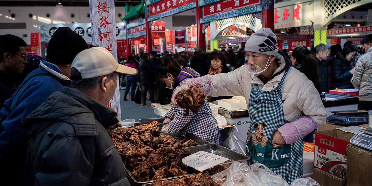 A vendor selling meat to customers at a market in Beijing in January 2020. Image: Getty, Nicolas Asfouri / AFP