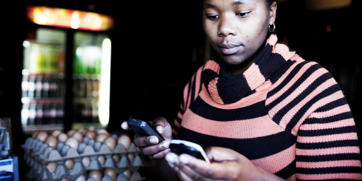 A shop owner makes a banking transaction on her mobile phone in Khayelitsha, Cape Town, South Africa. Image, Getty, Per-Anders Pettersson