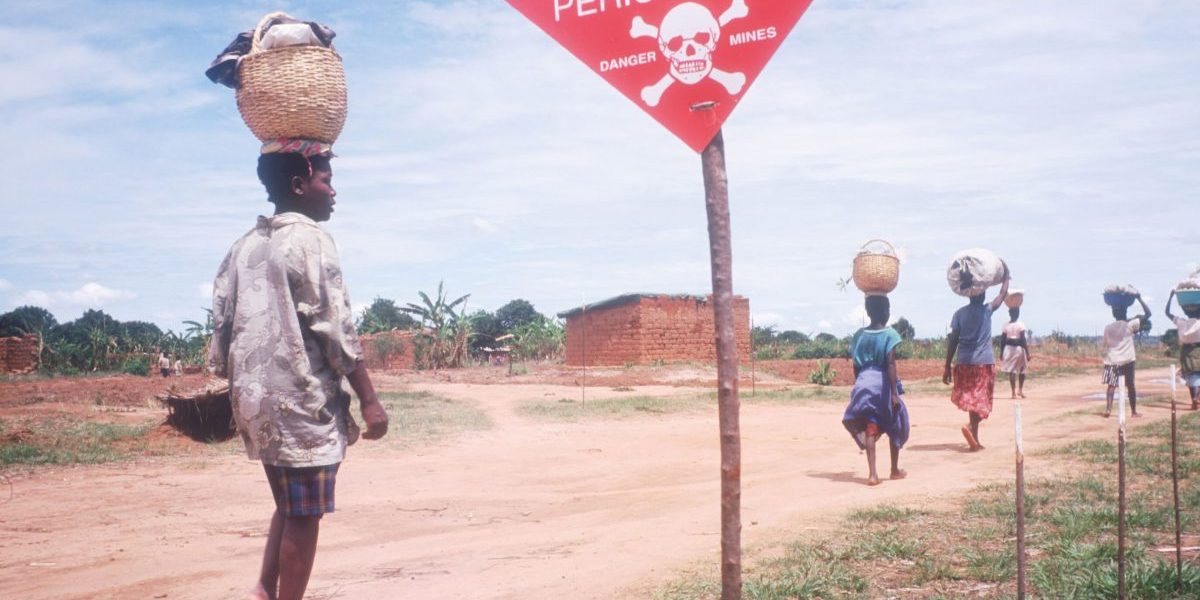 Men and women walk past a landmine field in Kuito, Angola in 1999.  Credit: Getty Images, Malcolm Linton/Liaison