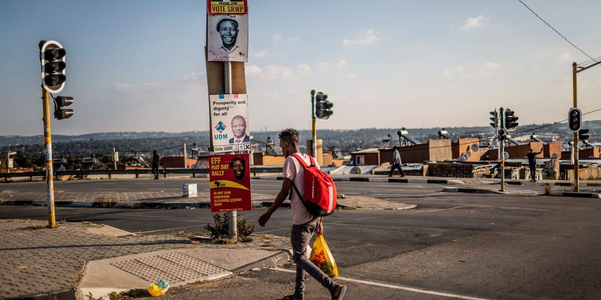A street scene shows a man crossing the road flanked by South African political party posters in the run up to elections on April 28, 2019 in Alexandra, Johannesburg. Image: Getty,  Gulshan Khan/AFP