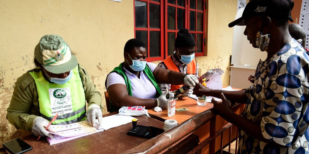 Officials of Independent National Electoral Commission (INEC) wearing protective masks screen a voter during the Edo State governorship elections in Benin City. Image: Getty, Pius Utomi Ekpei/AFP