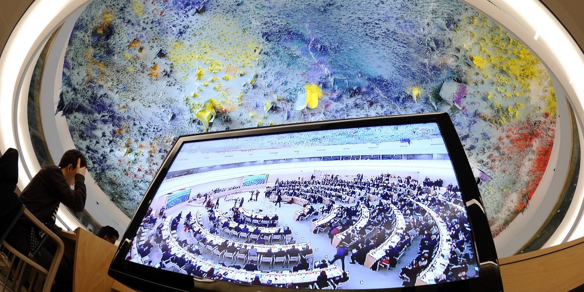 The assembly hall seen on a television screen during the opening of the 16th session of the United Nations Human Rights Council in Geneva, focusing on repression in Libya. Image: Getty, Fabrice Coffrini/AFP